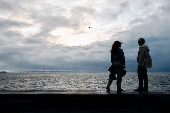 Ett par som står vid havet med Öresundsbron i bakgrunden